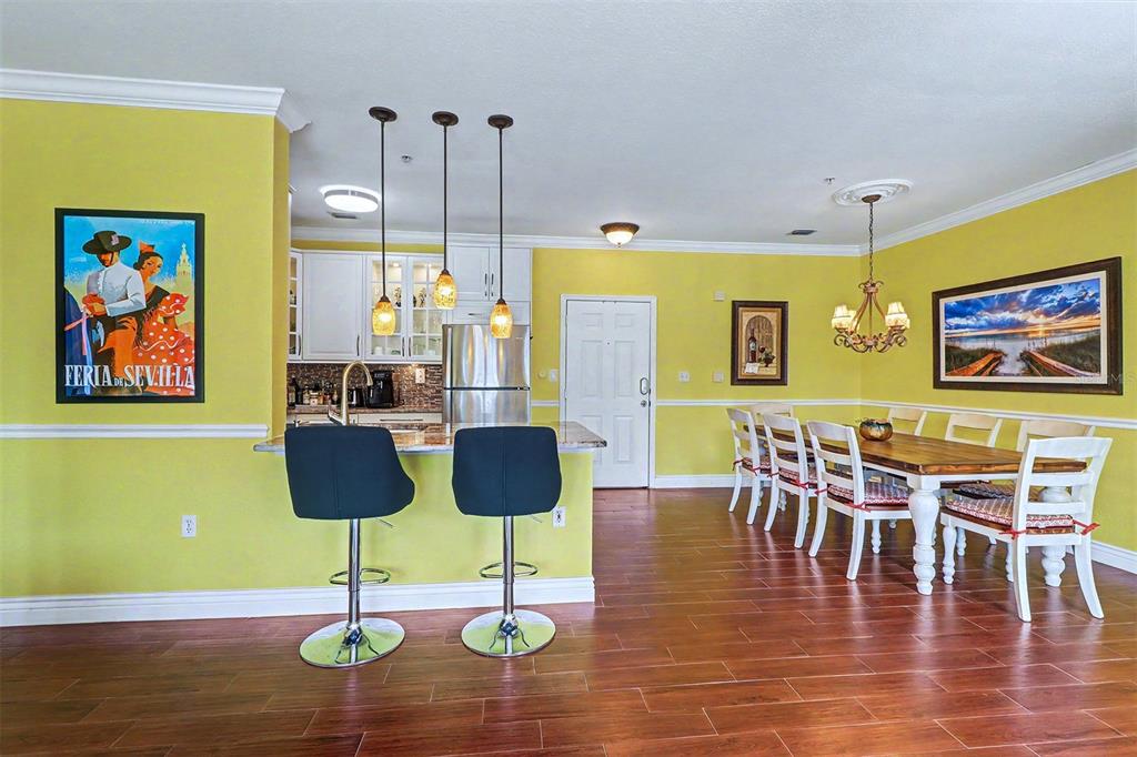 A kitchen and dining area with yellow walls, white cabinets, and wood-look tile floors — 2746 VIA TIVOLI UNIT 122B, CLEARWATER, FL