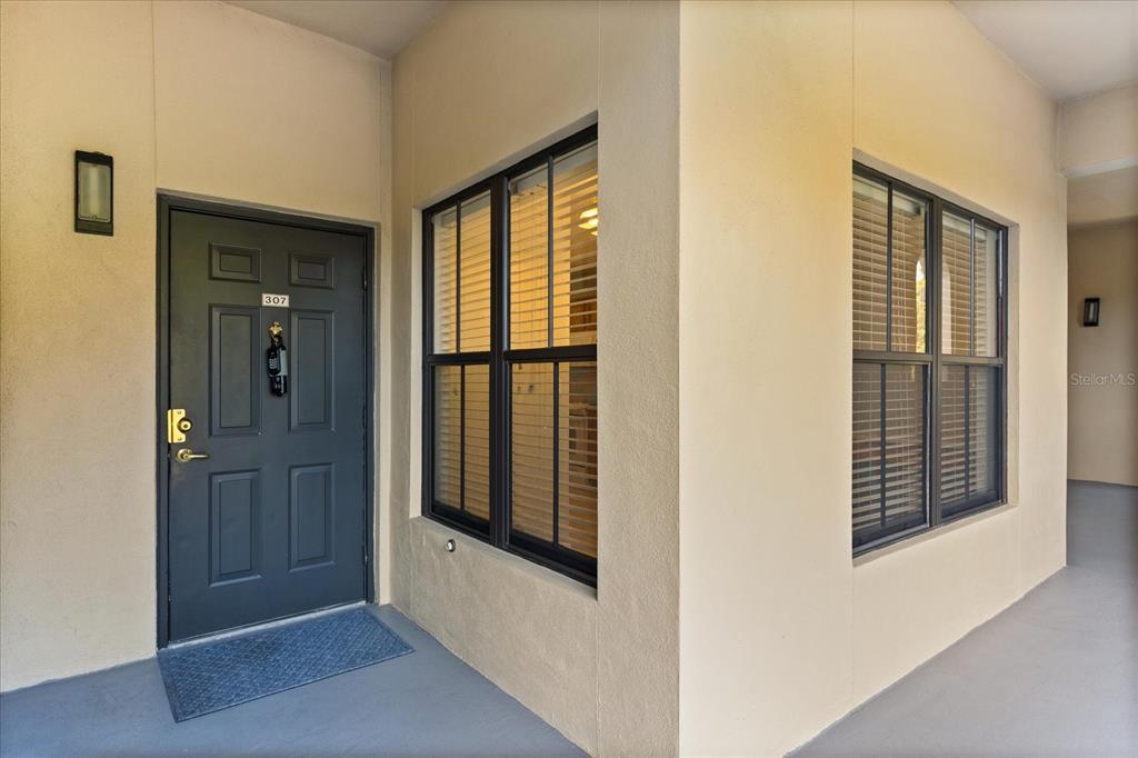 An exterior view of a residential unit entrance with a dark door and windows — 909 WATERSIDE LANE UNIT 307, CELEBRATION, FL
