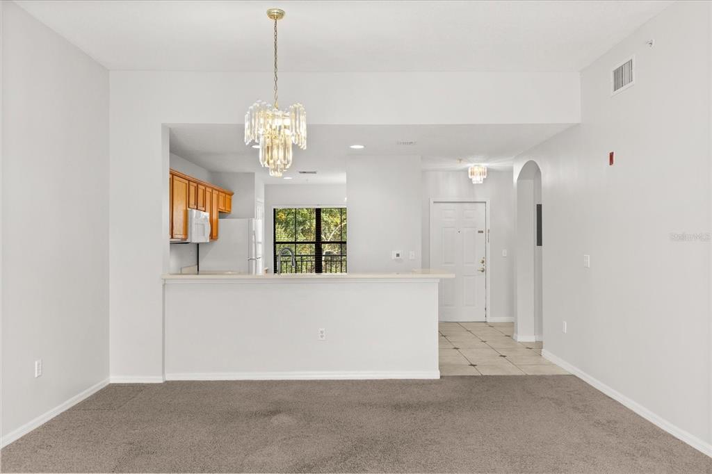 A living area opens to a kitchen with a breakfast bar and a crystal chandelier — 909 WATERSIDE LANE UNIT 307, CELEBRATION, FL
