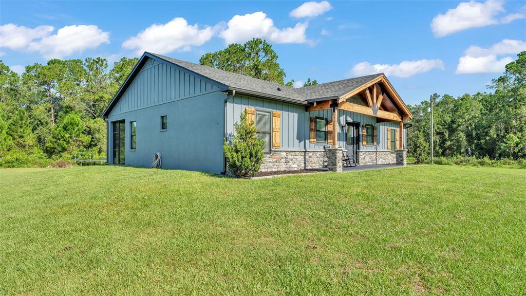 A single-story house with blue vertical siding, stone accents, and a wooden porch gable — 18940 COMMONWEALTH AVENUE N, POLK CITY, FL