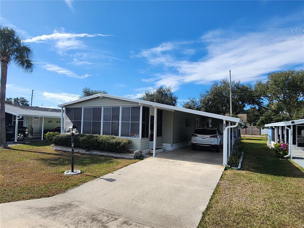 A light green manufactured home with a screened-in porch and a concrete carport — 188 SWEET CIRCLE DRIVE, WINTER HAVEN, FL