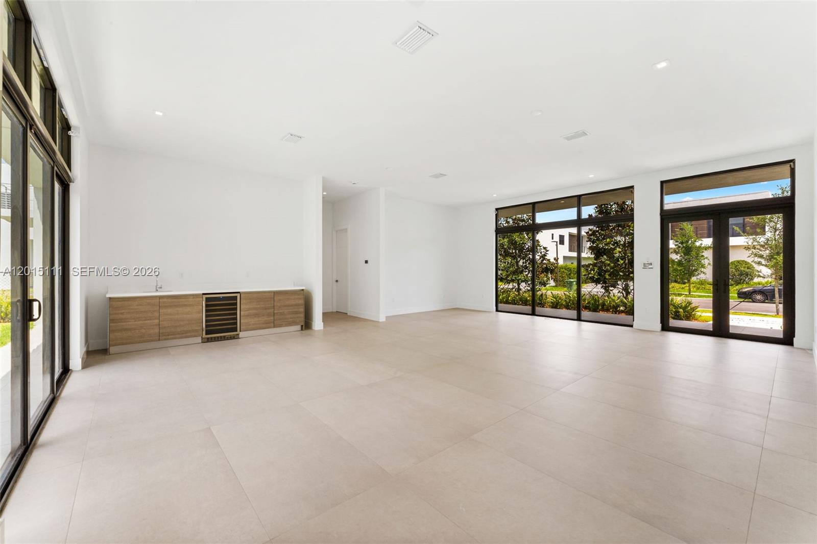 A spacious, modern living area features light tile floors, a wet bar, and large glass doors — 16700 N Botaniko Dr N, Weston FL 33326, WESTON, FL