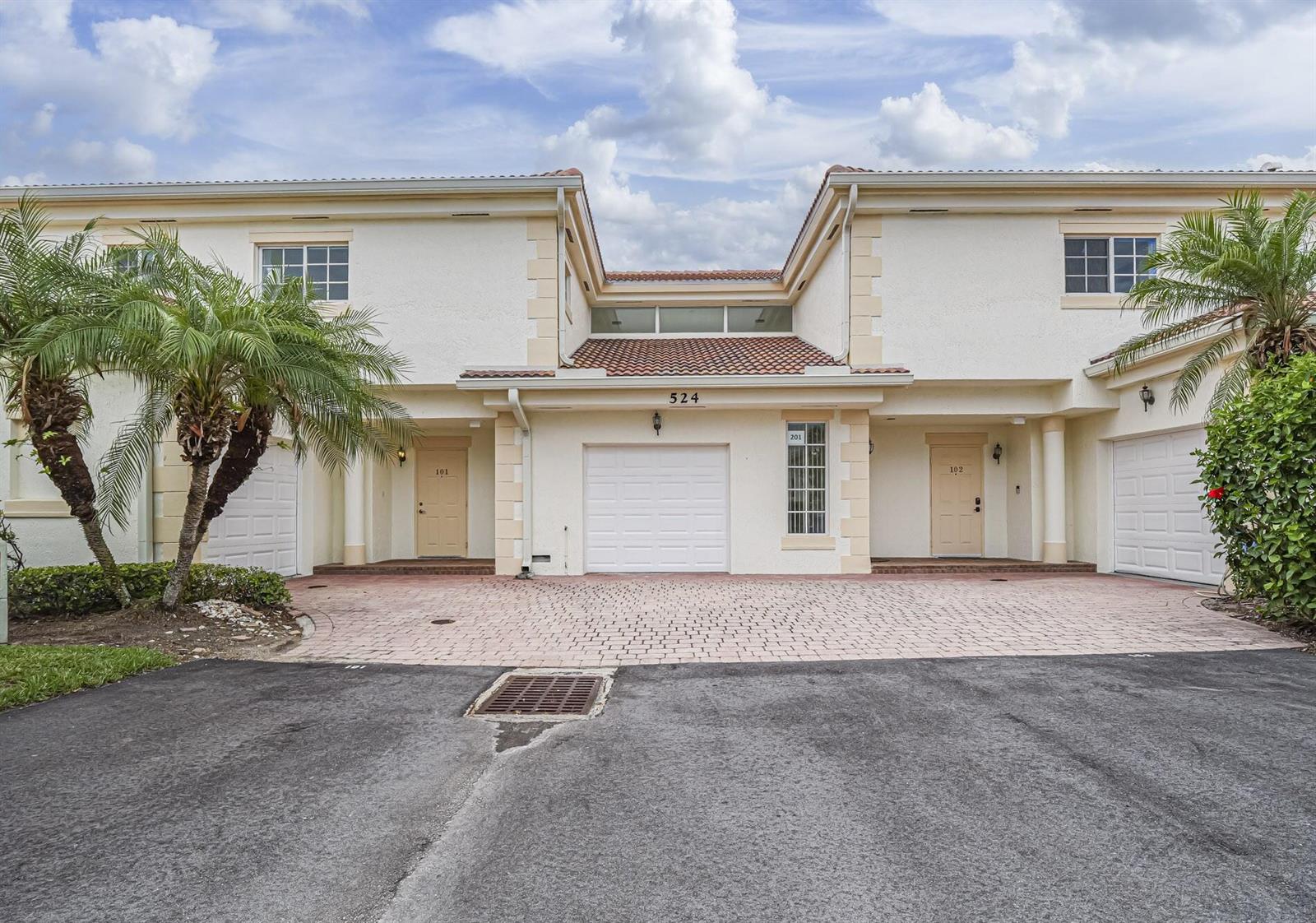 A two-story residential building with two tan doors, two garage doors, and palm trees — 524 7th Square # 101, Vero Beach FL 32962, VERO BEACH, FL