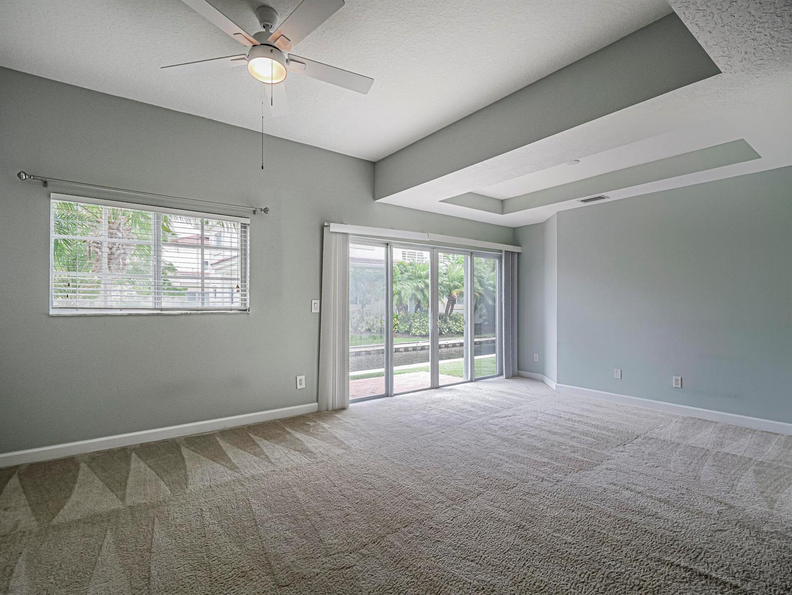 An empty room with light gray walls, carpeted flooring, a ceiling fan, and sliding glass doors — 524 7th Square # 101, Vero Beach FL 32962, VERO BEACH, FL