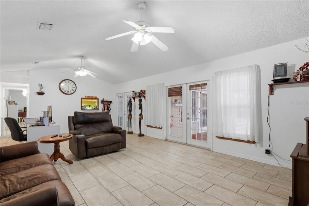 A living room with white walls, tile flooring, two ceiling fans, and brown leather furniture — 11808 FAWN DALE DRIVE, RIVERVIEW, FL