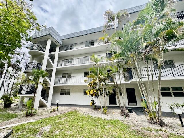 A three-story white apartment building features exterior staircases, balconies with black railings, and palm trees — 3300 Spanish Moss Terrace # 302, Lauderhill FL 33319, LAUDERHILL, FL