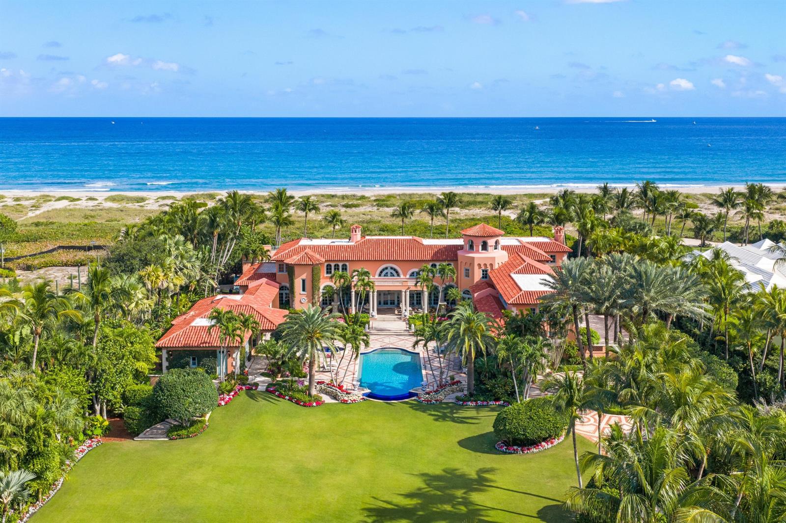 An aerial view of a large, peach-colored Mediterranean-style mansion with a pool and oceanfront lawn — 1491 N Ocean Boulevard, Palm Beach FL 33480, PALM BEACH, FL