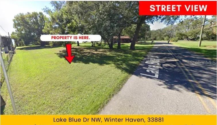 A grassy vacant lot sits beside a paved road under mature trees — LAKE BLUE DRIVE NW, WINTER HAVEN, FL