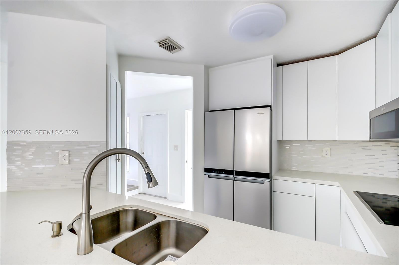 A modern kitchen features white cabinets, stainless steel appliances, and a double-basin sink — 12909 SW 61 # 0, Miami FL 33183, MIAMI, FL