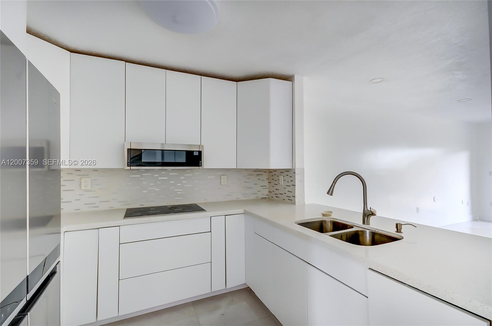 A modern kitchen features white flat-panel cabinets, stainless steel appliances, and a quartz countertop — 12909 SW 61 # 0, Miami FL 33183, MIAMI, FL