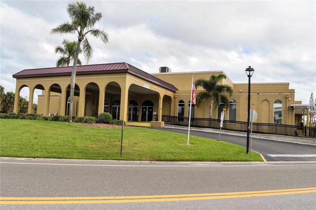 A yellow building with a covered arched entrance, palm trees, and a paved driveway — 2370 JAMAICAN STREET UNIT 54, CLEARWATER, FL