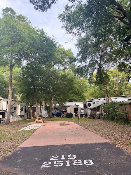 A paved driveway with painted numbers leads to a wooded area with several parked RVs — 25188 NE 142ND PLACE UNIT 219, FORT MC COY, FL