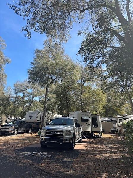 A silver pickup truck is parked in a wooded RV campsite with several trailers — 25188 NE 142ND PLACE UNIT 219, FORT MC COY, FL