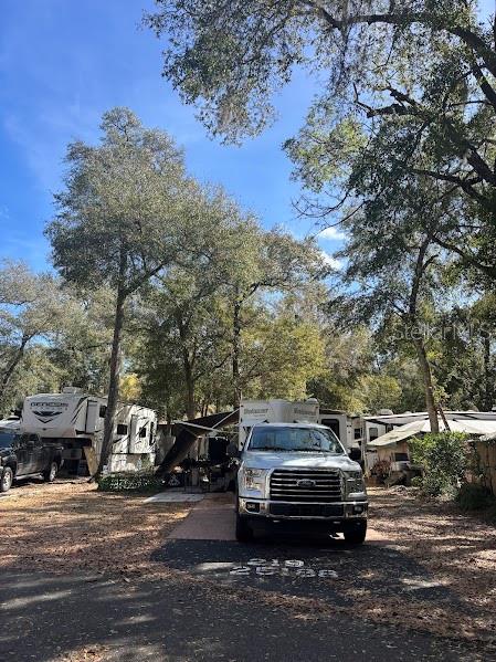 A silver Ford pickup truck is parked in front of a recreational vehicle under trees — 25188 NE 142ND PLACE UNIT 219, FORT MC COY, FL