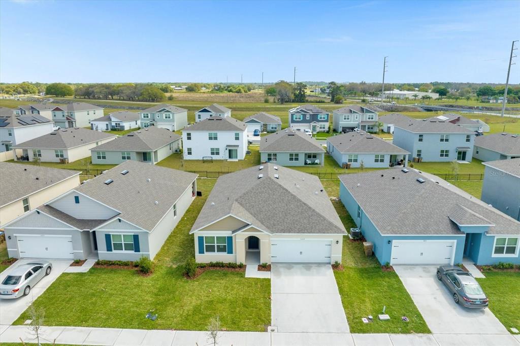 An aerial view of a suburban neighborhood featuring several single-family homes with driveways and lawns — 5209 BAROMBI BEND, ST CLOUD, FL