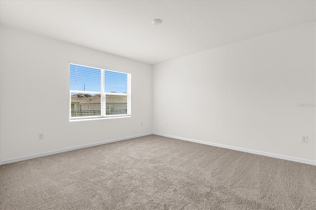 An empty bedroom features beige wall-to-wall carpeting, white walls, and a single window — 5209 BAROMBI BEND, ST CLOUD, FL