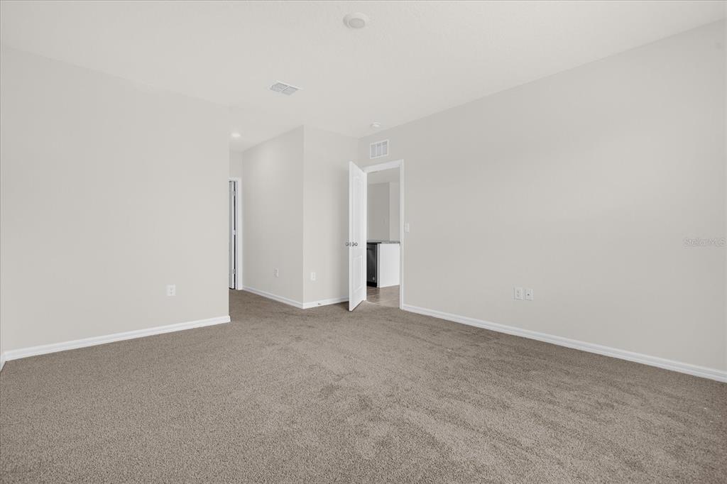 A carpeted room with light gray walls, a doorway, and an open entryway — 5209 BAROMBI BEND, ST CLOUD, FL