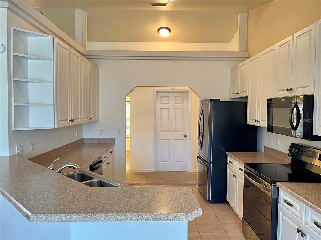 A kitchen features white cabinetry, tan laminate countertops, and black appliances — 19430 NW 164TH ROAD, HIGH SPRINGS, FL
