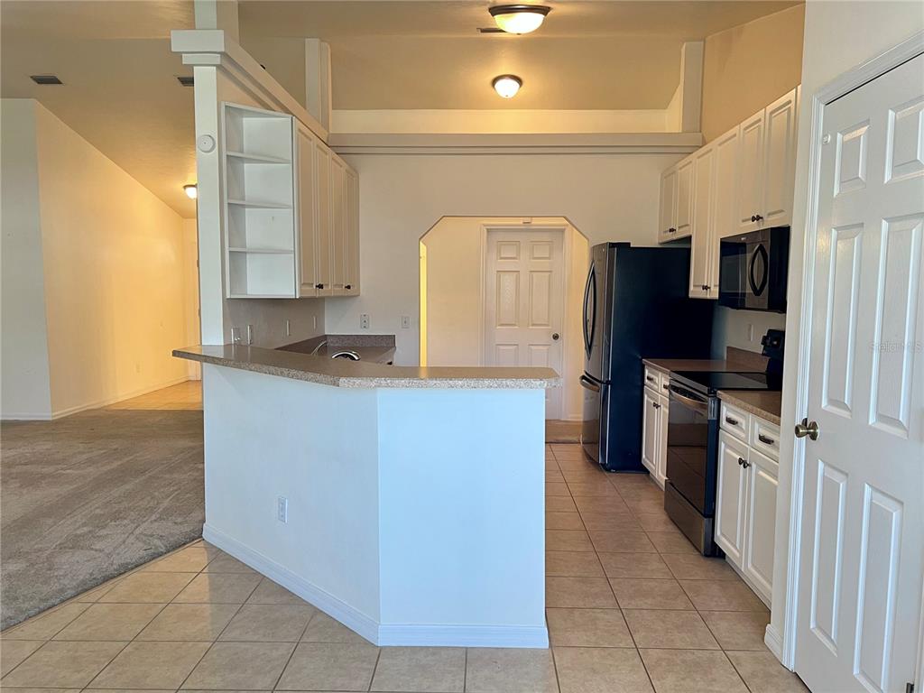 A kitchen with white cabinets, black appliances, and a breakfast bar overlooking a carpeted area — 19430 NW 164TH ROAD, HIGH SPRINGS, FL