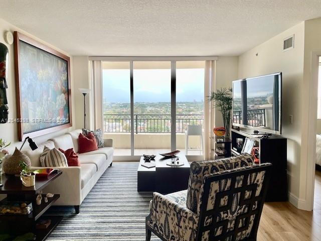 A living room features a white sofa, patterned armchair, television, and a balcony with views — 3232 SW 22nd Ter # 1303, Miami FL 33145, MIAMI, FL
