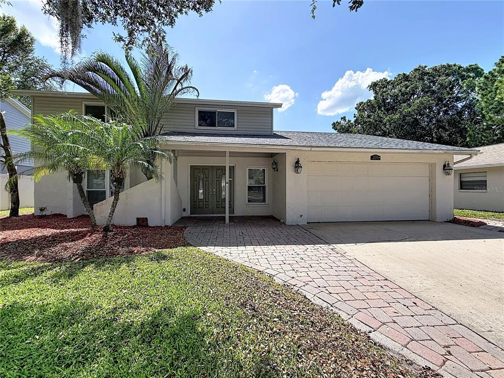 A two-story house with a paved driveway, a two-car garage, and a palm tree — 15708 WOODCOCK PLACE, TAMPA, FL