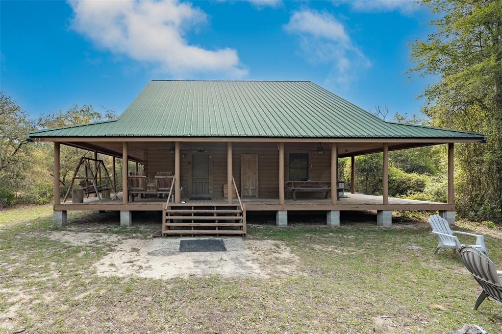 A log cabin with a large wrap-around porch and a green metal roof — 20259 NE 147TH TERRACE, FORT MC COY, FL