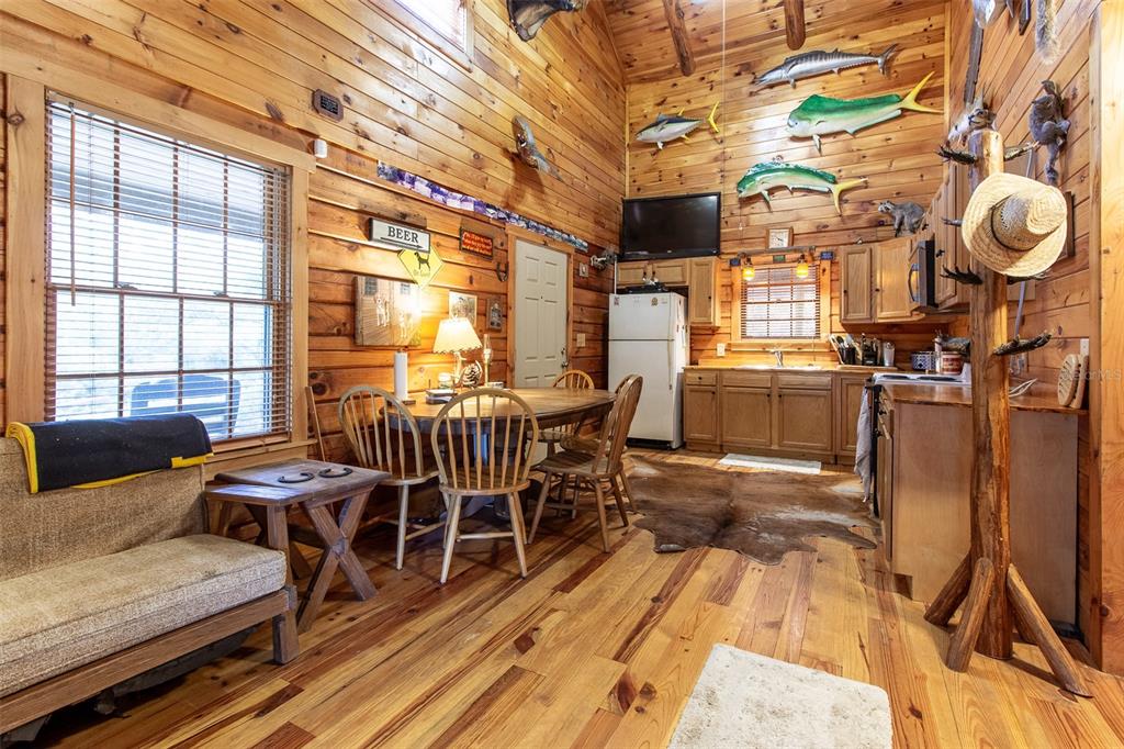 A rustic log cabin kitchen and dining area features wood walls, taxidermy fish, and flooring — 20259 NE 147TH TERRACE, FORT MC COY, FL