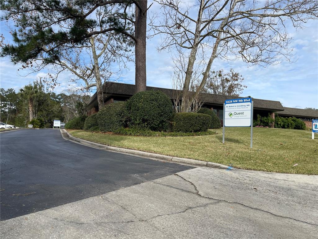 A low-rise commercial building features a paved driveway, manicured landscaping, and a prominent signage post — 6628 NW 9TH BOULEVARD NW UNIT 4, GAINESVILLE, FL
