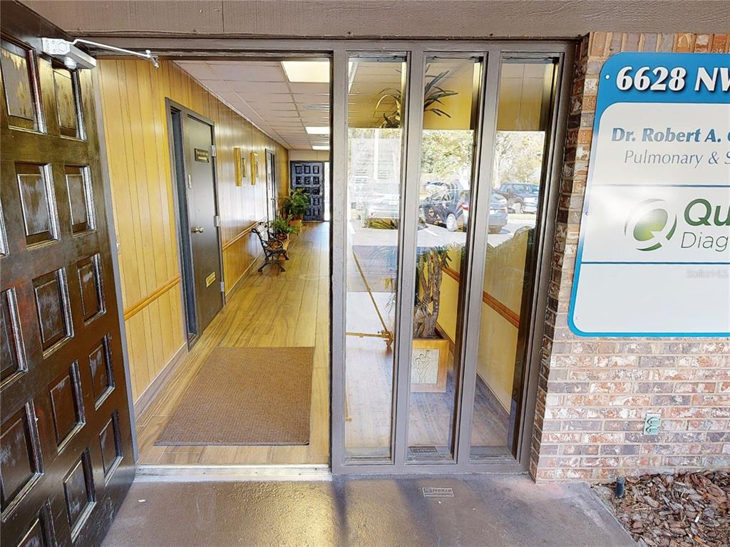 An open doorway leads into a wood-paneled hallway with a brown mat and a bench — 6628 NW 9TH BOULEVARD NW UNIT 4, GAINESVILLE, FL