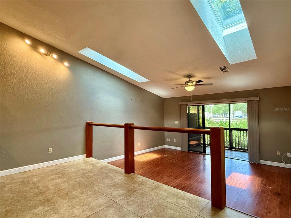 A split-level room features a tiled upper area, a wooden-floored lower area, and skylights — 6437 93RD TERRACE N UNIT 5003, PINELLAS PARK, FL