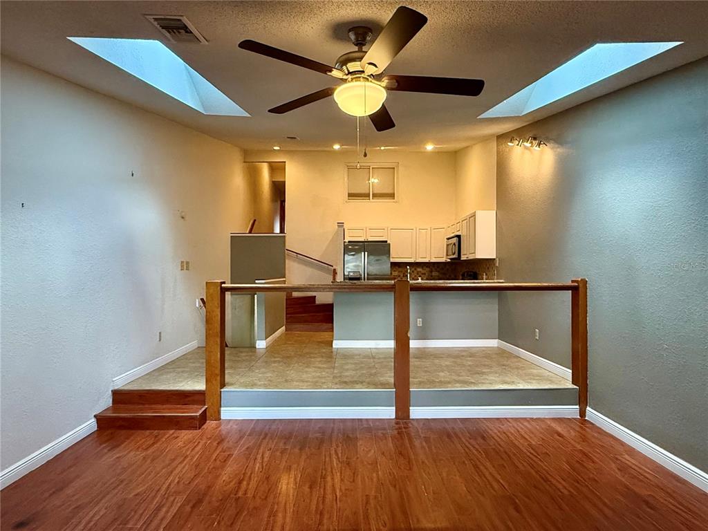 A split-level room features wood flooring, a raised kitchen area with tile, and skylights — 6437 93RD TERRACE N UNIT 5003, PINELLAS PARK, FL