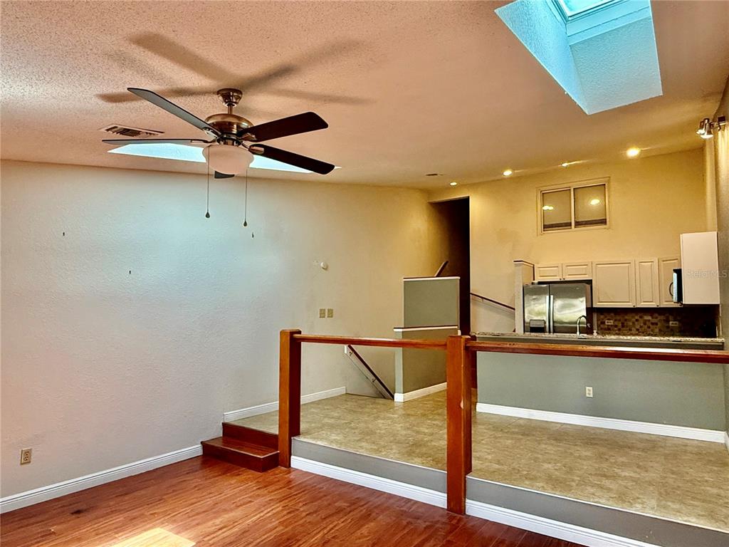A sunken living room with wood flooring leads up to a kitchen with tile flooring — 6437 93RD TERRACE N UNIT 5003, PINELLAS PARK, FL