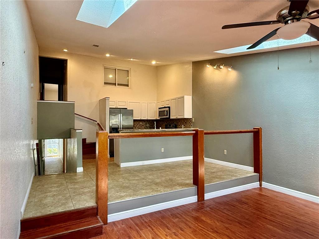 A split-level room features a kitchen with white cabinets and tile flooring above a living area — 6437 93RD TERRACE N UNIT 5003, PINELLAS PARK, FL