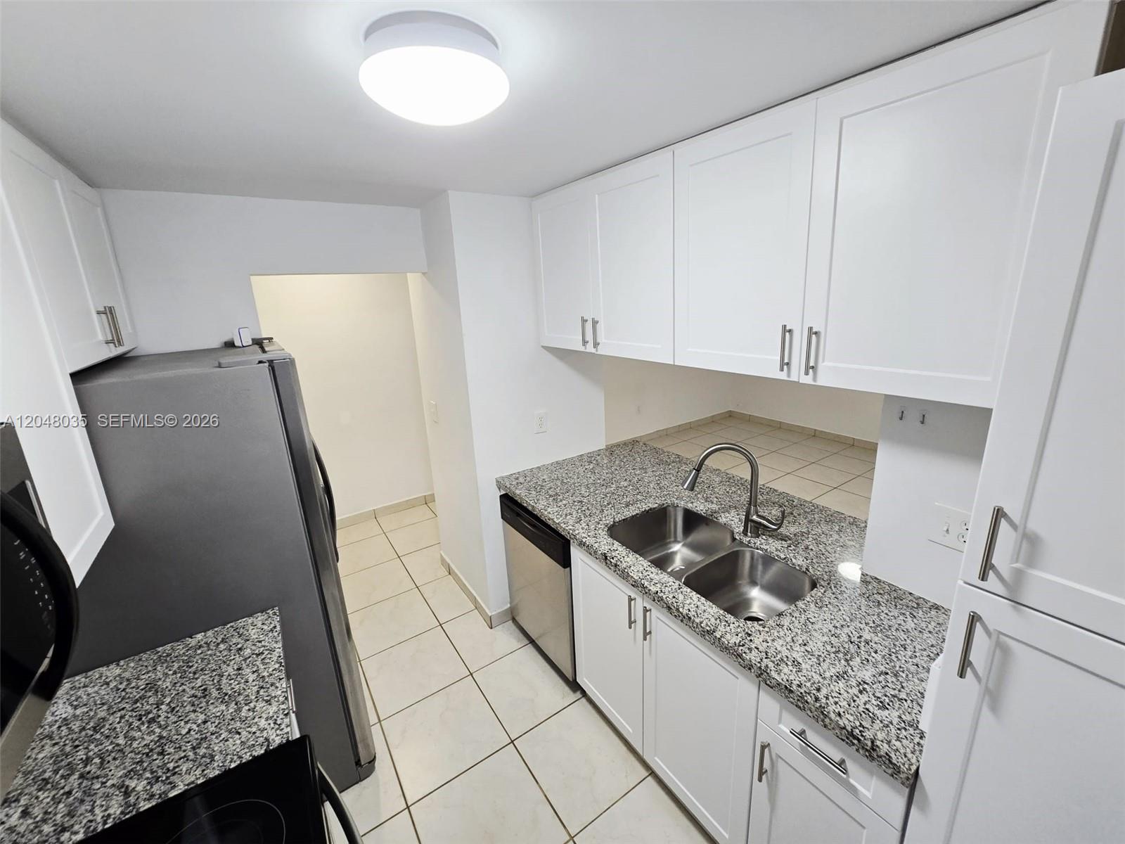 A kitchen features white cabinets, granite countertops, stainless steel appliances, and light-colored floor tiles — 8877 Fontainebleau Blvd # 202, Miami FL 33172, MIAMI, FL
