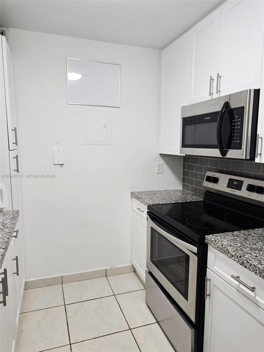 A galley kitchen features white cabinets, granite countertops, stainless steel appliances, and tiled flooring — 8877 Fontainebleau Blvd # 202, Miami FL 33172, MIAMI, FL