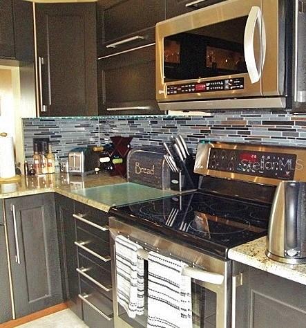 A kitchen features dark wood cabinets, stainless steel appliances, and a multi-colored glass tile backsplash — 6294 BAHIA DEL MAR CIRCLE UNIT 215, ST PETERSBURG, FL