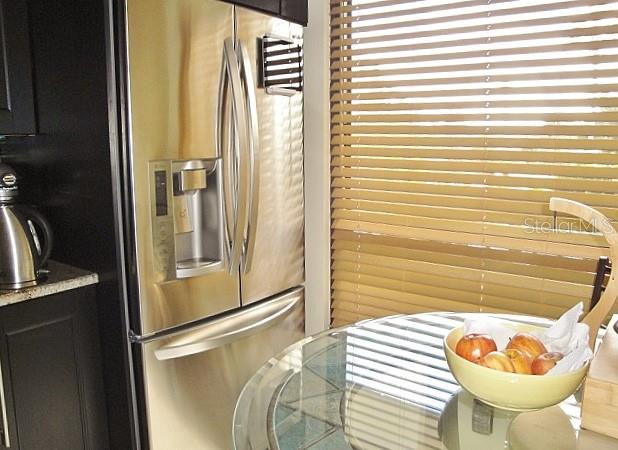 A stainless steel refrigerator stands next to a glass-topped table with a bowl of apples — 6294 BAHIA DEL MAR CIRCLE UNIT 215, ST PETERSBURG, FL