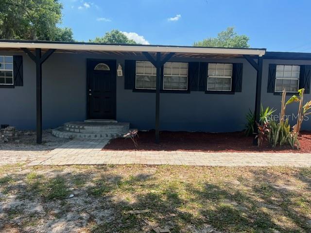 A gray house features a covered front porch, a black door, and a brick walkway — 5580 STATE ROAD 542 W, WINTER HAVEN, FL