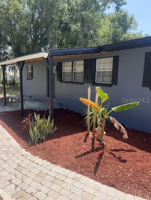 A gray house exterior features a covered porch, dark shutters, and a brick paver walkway — 5580 STATE ROAD 542 W, WINTER HAVEN, FL