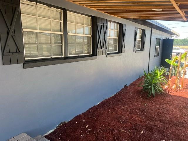 Exterior view of a gray house with black shutters and a red mulch garden bed — 5580 STATE ROAD 542 W, WINTER HAVEN, FL
