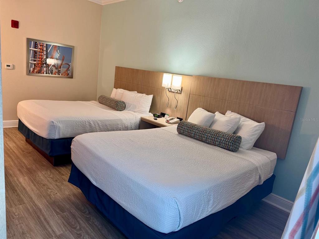 A hotel room features two queen beds with white linens, a shared nightstand, and wood-look flooring — 3000 MAINGATE LN UNIT 319, KISSIMMEE, FL