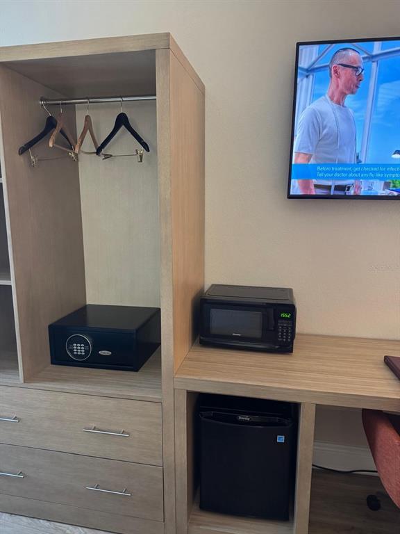 A hotel room features a wooden wardrobe with a safe, a microwave, and a mini-fridge — 3000 MAINGATE LN UNIT 319, KISSIMMEE, FL