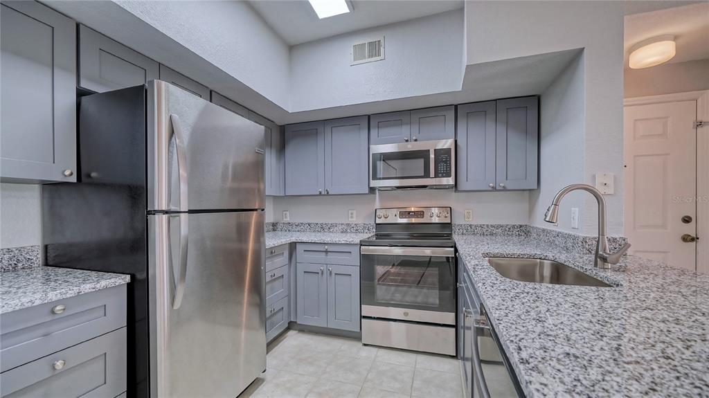 A kitchen features gray cabinets, granite countertops, and stainless steel appliances — 4160 CENTRAL SARASOTA PARKWAY UNIT 614, SARASOTA, FL
