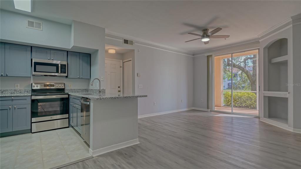 A kitchen with blue cabinets and stainless steel appliances opens to a living area — 4160 CENTRAL SARASOTA PARKWAY UNIT 614, SARASOTA, FL