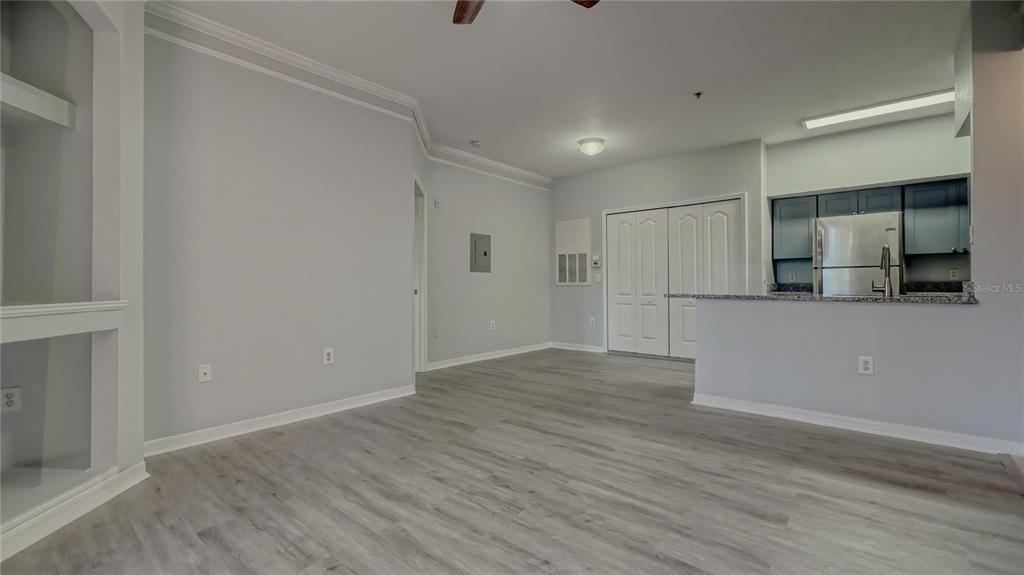 An open-concept living area with light gray walls, wood-look flooring, and an adjacent kitchen — 4160 CENTRAL SARASOTA PARKWAY UNIT 614, SARASOTA, FL