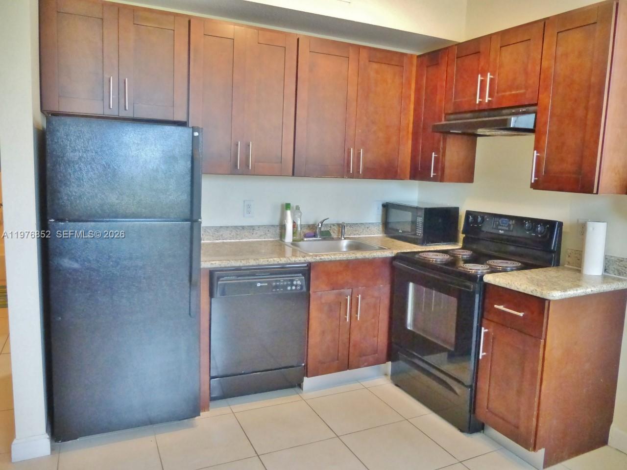 A kitchen features dark wood cabinets, black appliances, and light-colored granite countertops — 843 SW 13th AV # 201, Miami FL 33135, MIAMI, FL