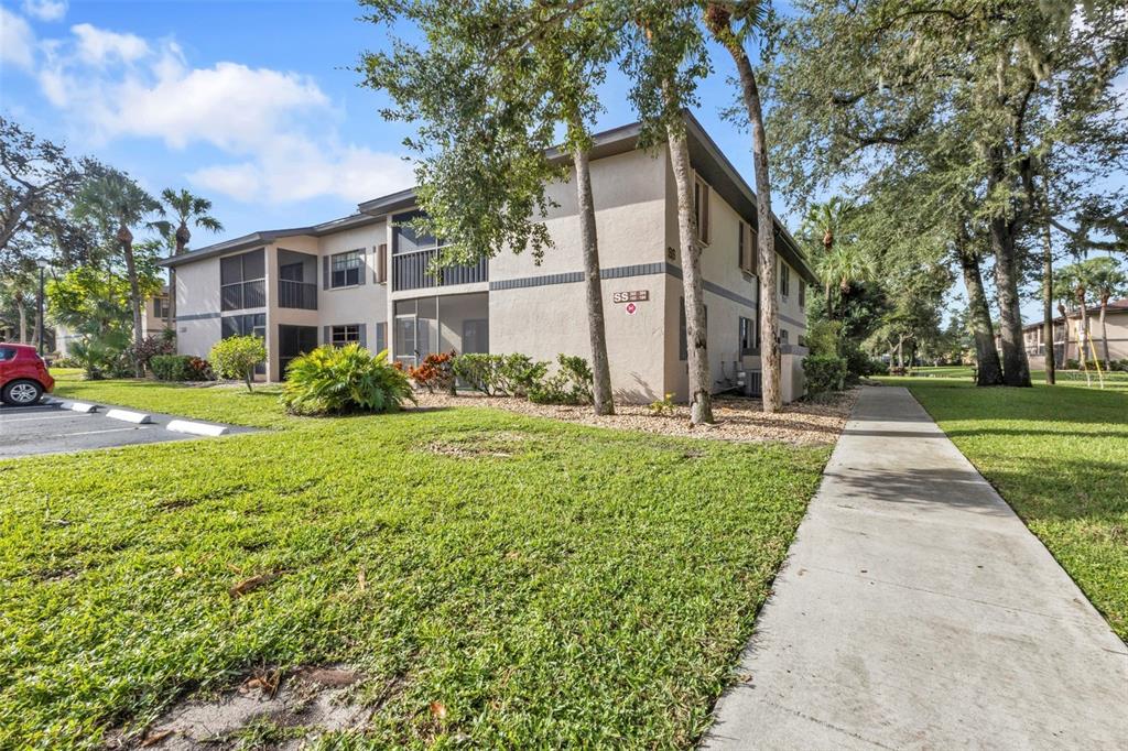 A two-story apartment building with screened balconies and a concrete walkway on a sunny day — 19505 QUESADA AVENUE UNIT SS103, PORT CHARLOTTE, FL