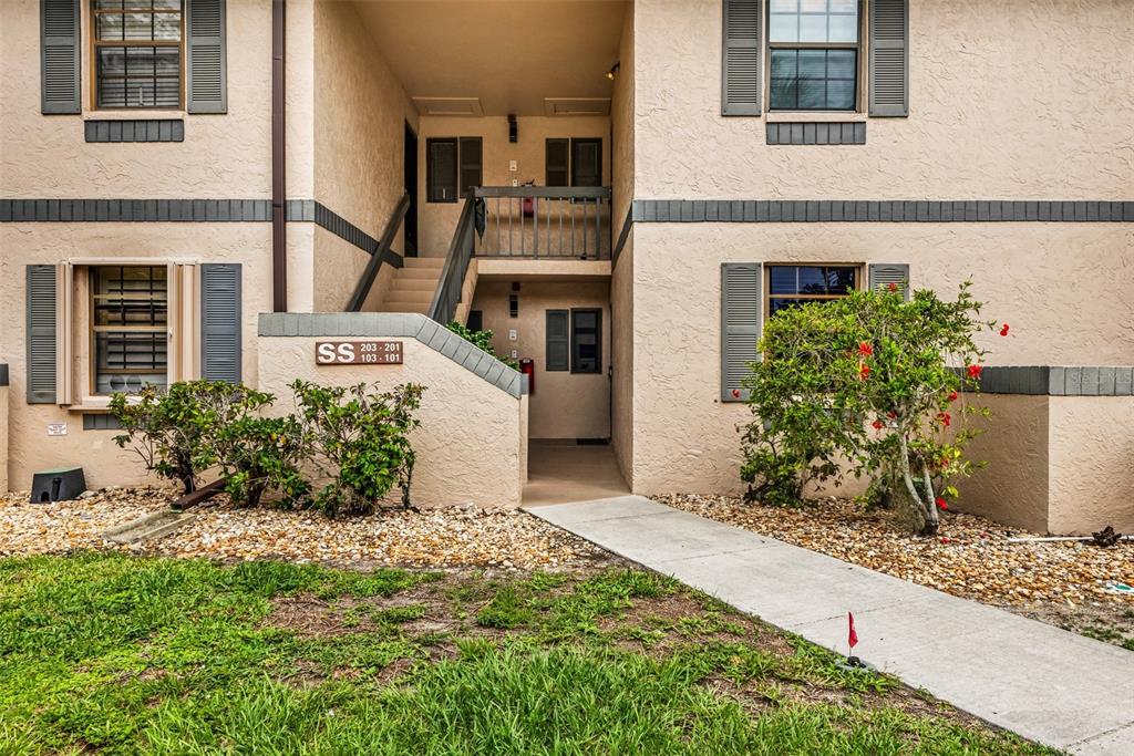An exterior view of a two-story apartment building with a concrete walkway and stairs — 19505 QUESADA AVENUE UNIT SS103, PORT CHARLOTTE, FL