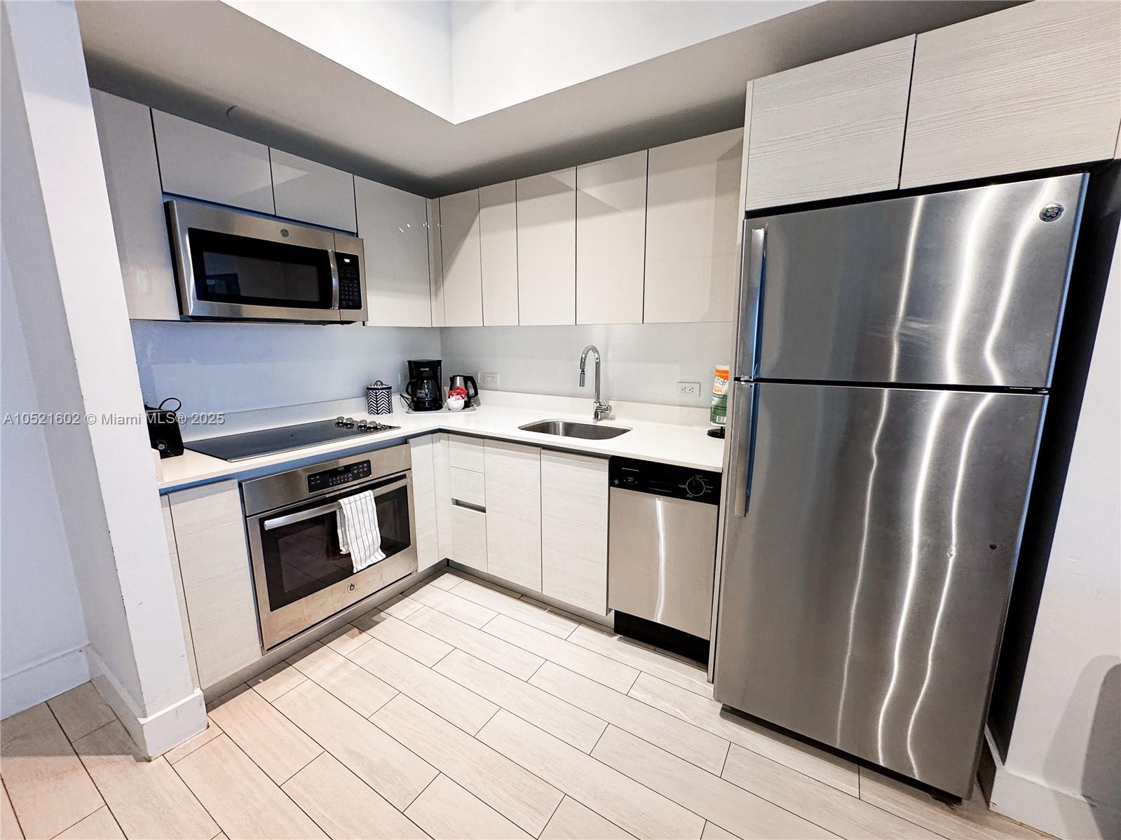 A modern kitchen features stainless steel appliances, light wood-grain cabinetry, and white countertops — 2600 E Hallandale Beach # 3104, Hallandale Beach FL 33009, HALLANDALE BEACH, FL