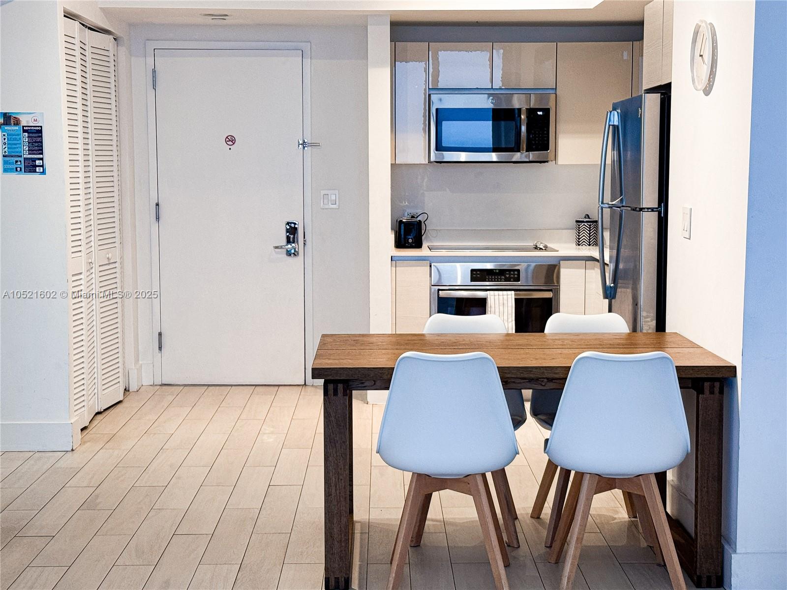 A small kitchen with stainless steel appliances sits next to a wooden dining table — 2600 E Hallandale Beach # 3104, Hallandale Beach FL 33009, HALLANDALE BEACH, FL